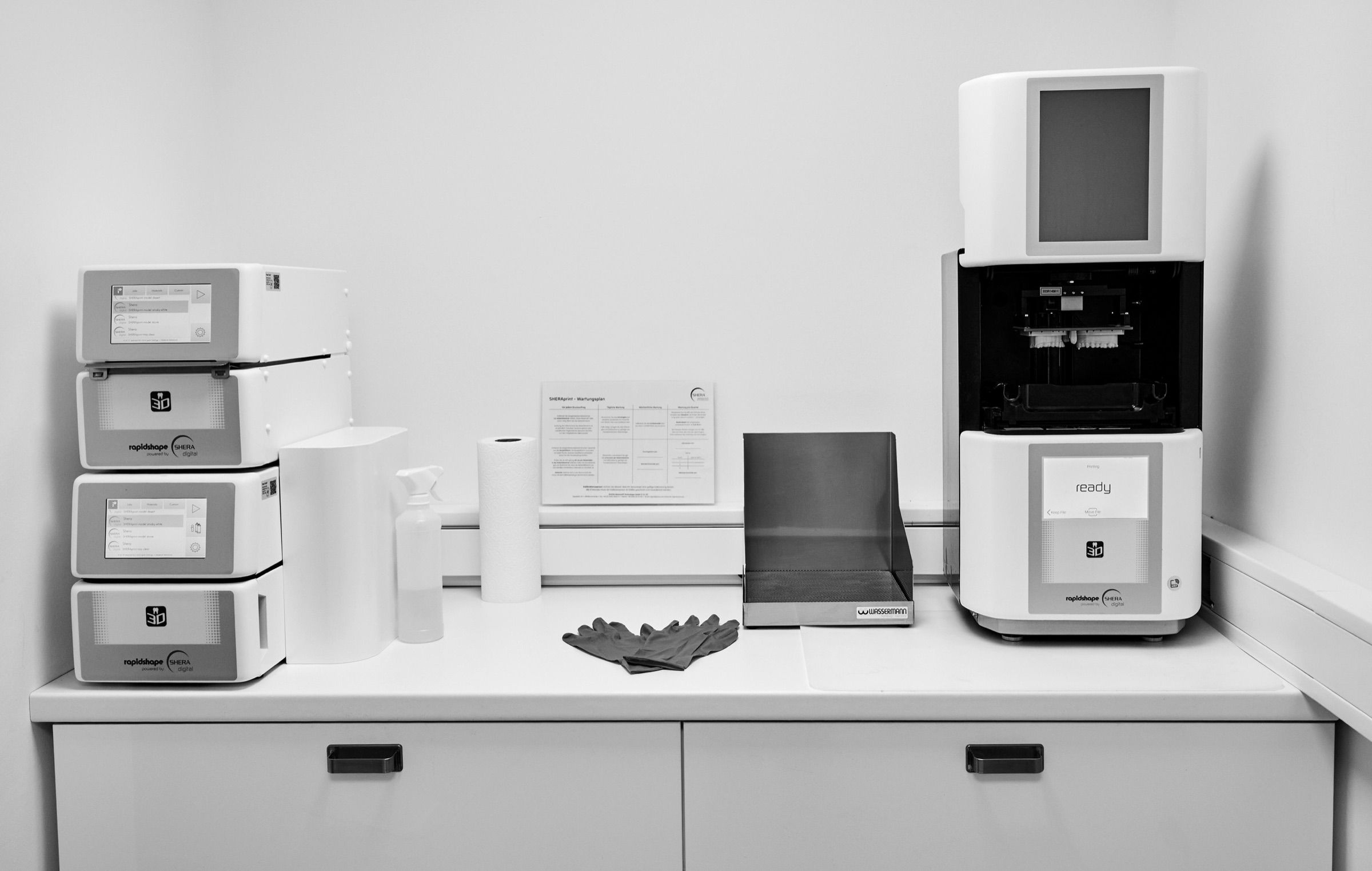 Zwei 3D-Drucker mit Nachhärtegeräten auf der Arbeitsfläche
